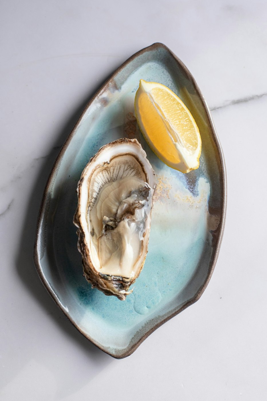 Freshly shucked oyster with lemon on artisanal ceramic dish